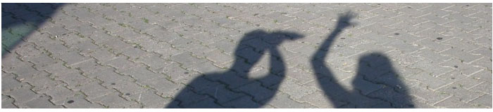 Fotostreifen: zwei Schatten auf Pflastersteinen, einer winkt